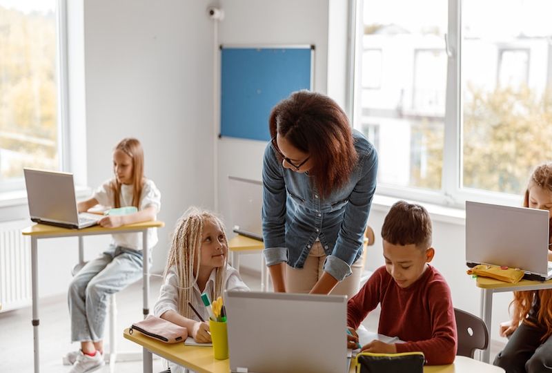 Female teacher explaining the task to schoolchildren