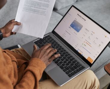 Vertical high angle view at African-American man using laptop with online banking service on screen, copy space