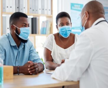 African american married couple in consult for fertility treatment. Medical doctor talking to a cou.