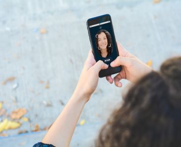 Woman unlocking smartphone with facial recognition technology. Biometric verification and face recognition concept. All screen graphics are made up by us